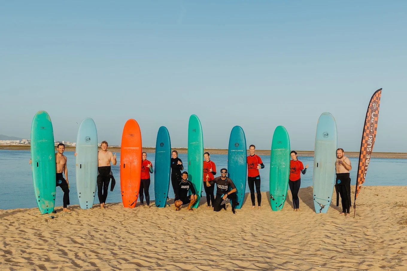Grupo da Salty Experiences com pranchas de surf na Praia de Faro.